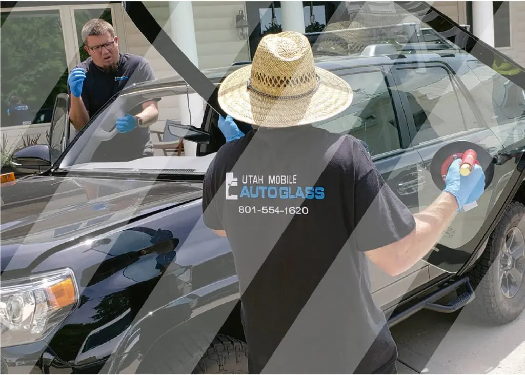 A man in a hat and gloves cleaning a car window, with a logo visible on the car's windshield.