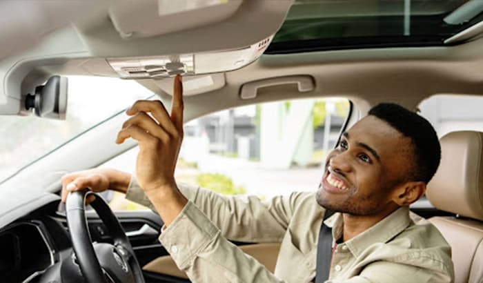 A man with a cheerful expression driving a car, displaying a contented smile on his face.