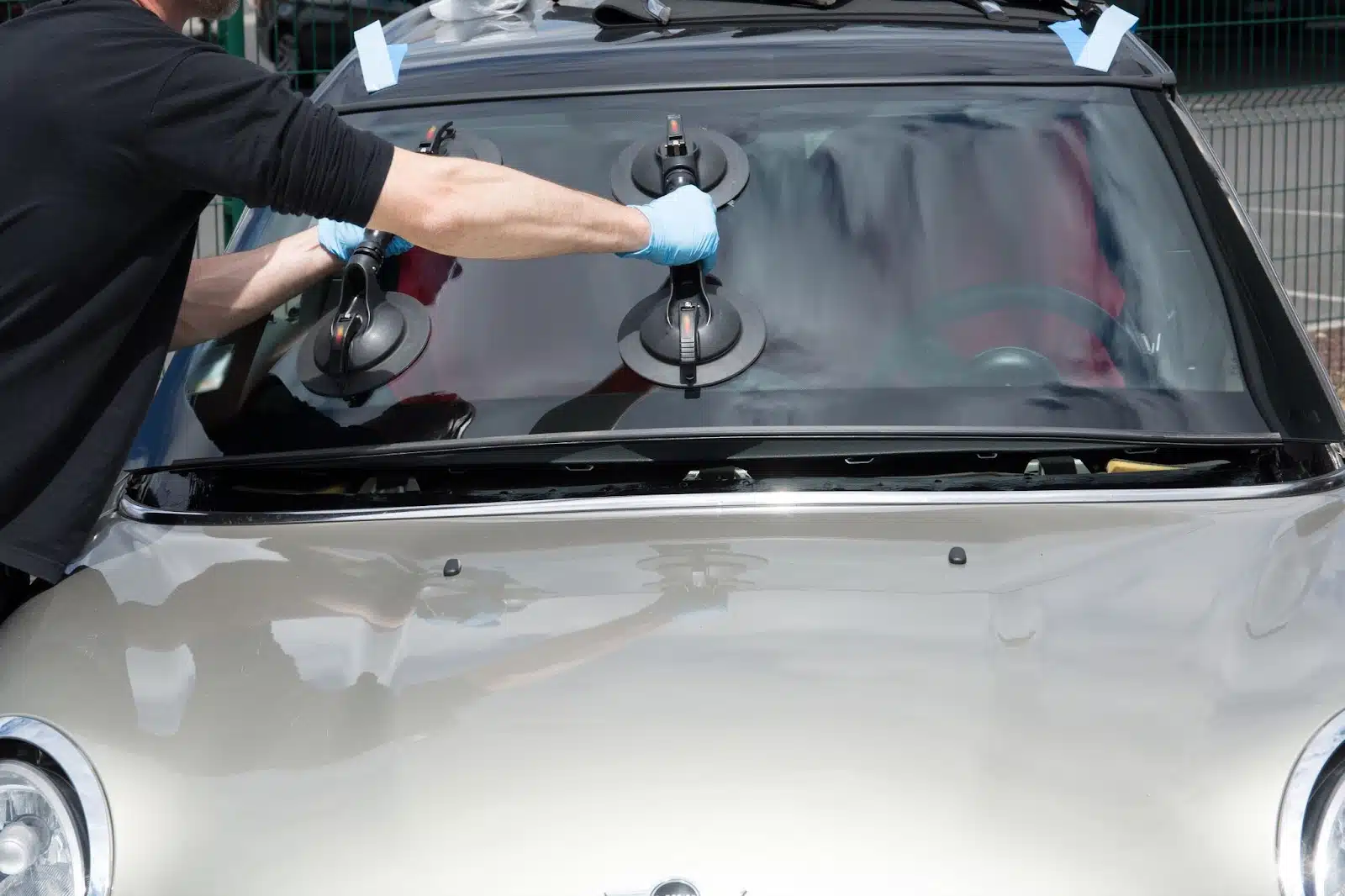 Windshield repair in progress by a man on a car.